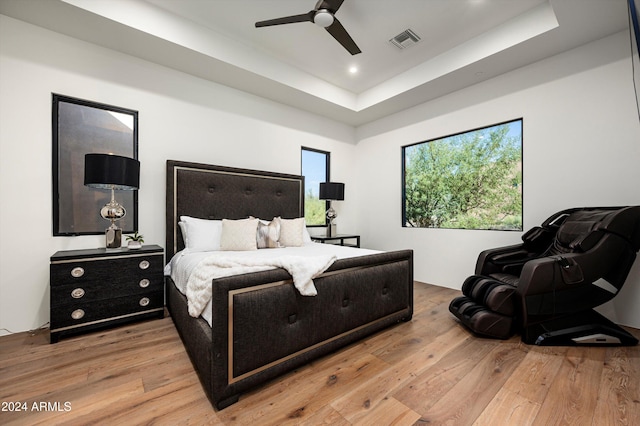 bedroom featuring wood-type flooring, a tray ceiling, and ceiling fan