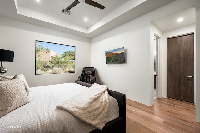 bedroom featuring a tray ceiling, ceiling fan, a closet, and light wood-type flooring