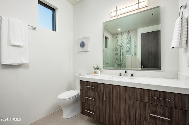 bathroom featuring tile patterned floors, vanity, toilet, and a shower with door