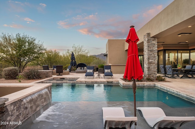 pool at dusk with a patio area