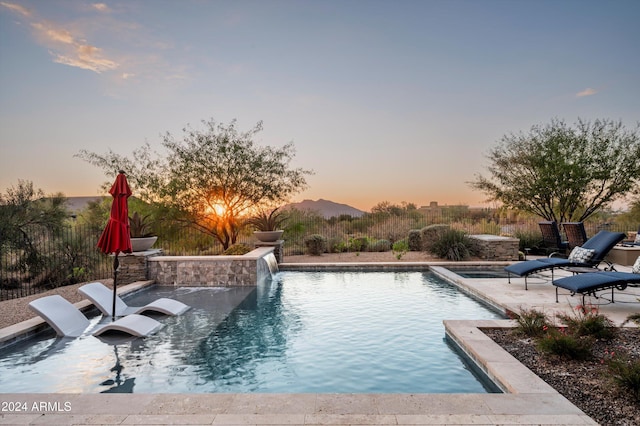 pool at dusk featuring pool water feature