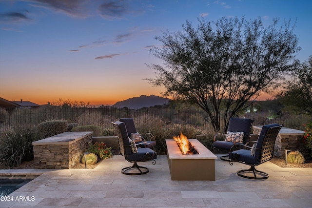 patio terrace at dusk featuring a mountain view and an outdoor fire pit