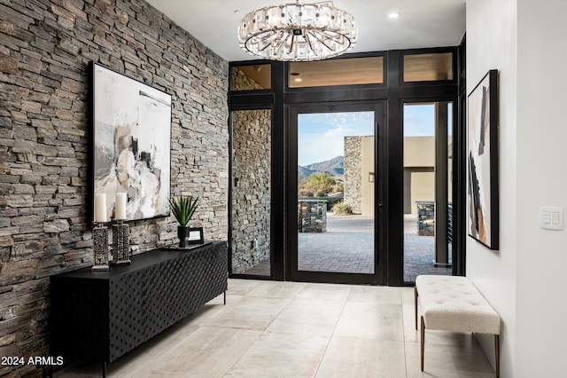 foyer entrance featuring a mountain view, light tile patterned flooring, and a notable chandelier