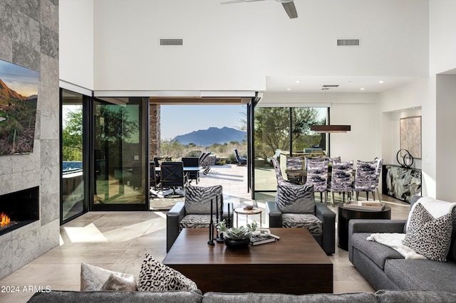 living room featuring a mountain view, a towering ceiling, a tile fireplace, and plenty of natural light