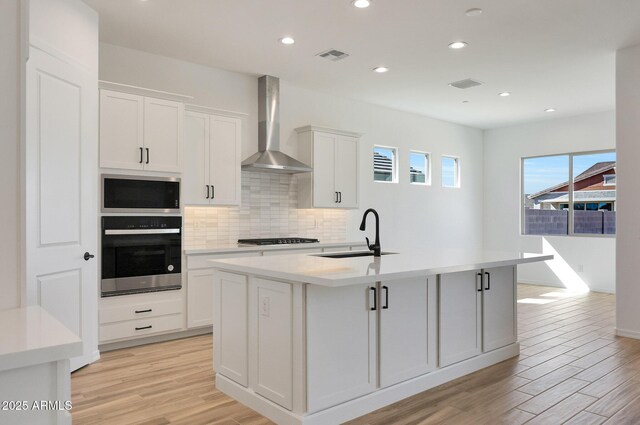 28266 N 134th Dr, Peoria, AZ 85383 - kitchen featuring light wood finished floors, visible vents, stainless steel appliances, wall chimney exhaust hood, and a sink