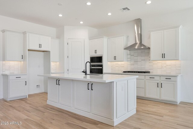28266 N 134th Dr, Peoria, AZ 85383 - kitchen featuring a kitchen island with sink, wall chimney exhaust hood, visible vents, and white cabinetry