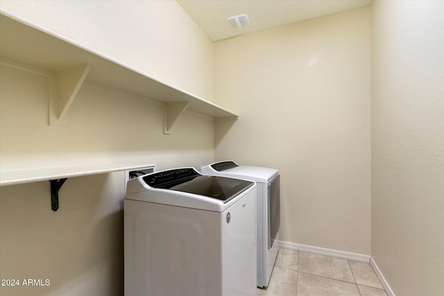 clothes washing area with light tile patterned flooring and separate washer and dryer