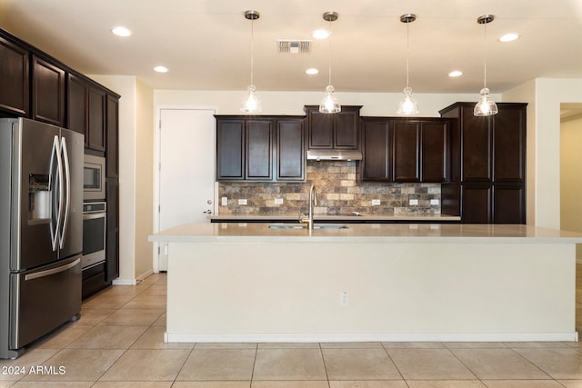 kitchen with dark brown cabinetry, stainless steel appliances, a kitchen island with sink, sink, and pendant lighting