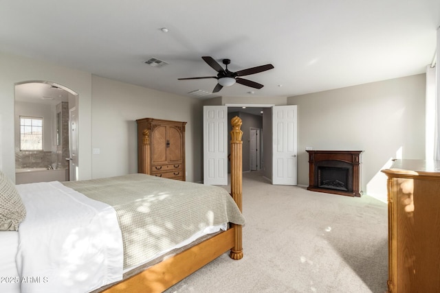 carpeted bedroom with ceiling fan and ensuite bath