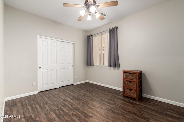 unfurnished bedroom featuring dark wood-type flooring, ceiling fan, and a closet