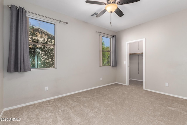 unfurnished bedroom with a spacious closet, light carpet, ceiling fan, and a closet