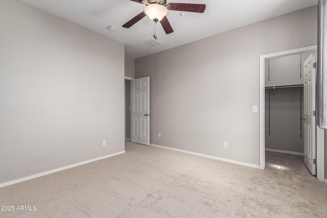 unfurnished bedroom with ceiling fan, a walk in closet, light colored carpet, and a closet