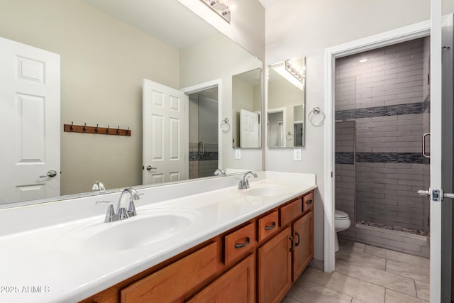 bathroom with a shower with door, vanity, tile patterned flooring, and toilet