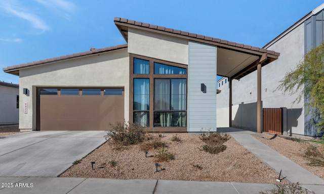 view of front of house with a garage, driveway, fence, and stucco siding