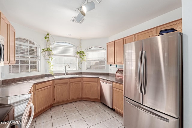 kitchen with stainless steel appliances, sink, light tile patterned floors, and light brown cabinetry