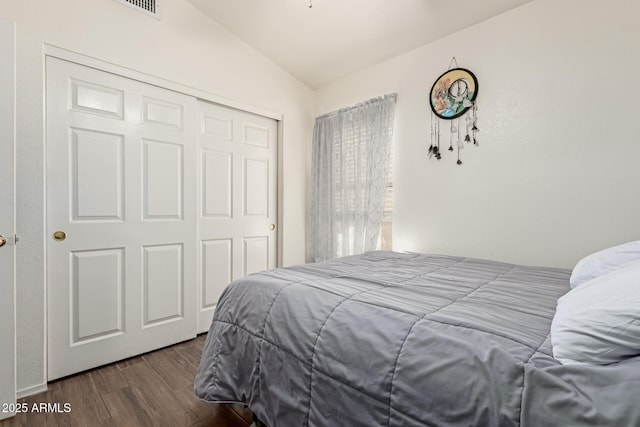 bedroom with lofted ceiling, dark hardwood / wood-style floors, and a closet