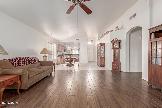 living room with dark hardwood / wood-style flooring, ceiling fan with notable chandelier, and high vaulted ceiling