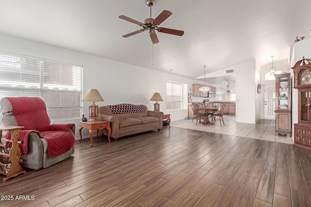 living room featuring vaulted ceiling, ceiling fan with notable chandelier, and hardwood / wood-style floors