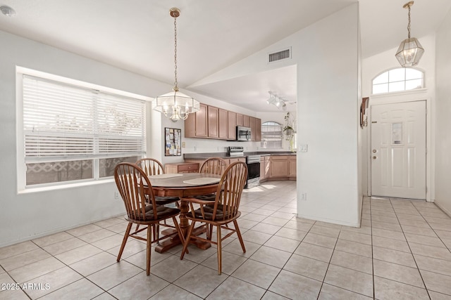 tiled dining room featuring vaulted ceiling and an inviting chandelier