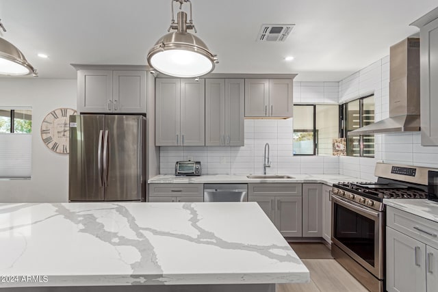 kitchen featuring sink, gray cabinetry, light hardwood / wood-style flooring, wall chimney exhaust hood, and stainless steel appliances