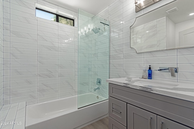 bathroom with vanity, tile walls, tiled shower / bath combo, and decorative backsplash