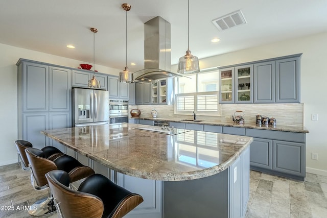 kitchen featuring a kitchen island, appliances with stainless steel finishes, decorative light fixtures, sink, and island exhaust hood