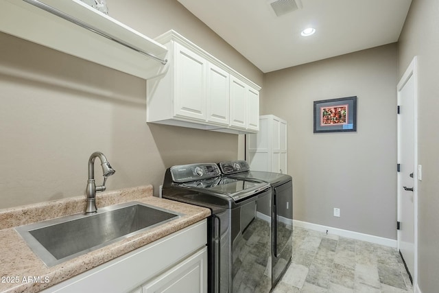 clothes washing area featuring cabinets, sink, and washer and dryer