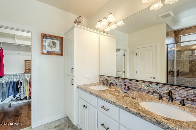 bathroom with vanity, backsplash, and walk in shower