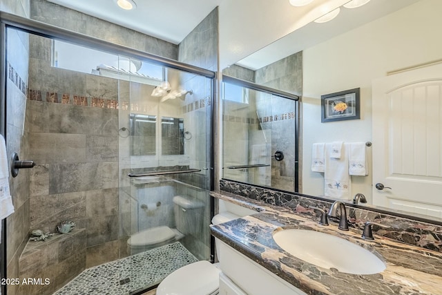 bathroom featuring vanity, an enclosed shower, and toilet