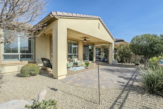 rear view of house featuring ceiling fan and a patio area