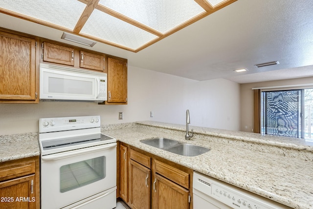 kitchen featuring white appliances, kitchen peninsula, and sink