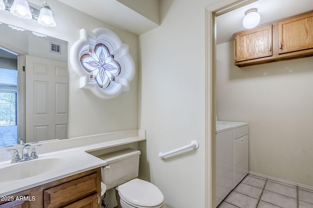 bathroom with independent washer and dryer, tile patterned floors, toilet, and vanity