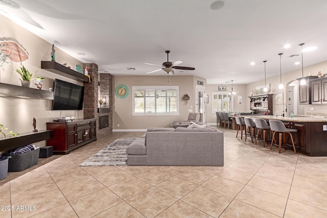 tiled living room with sink and ceiling fan with notable chandelier