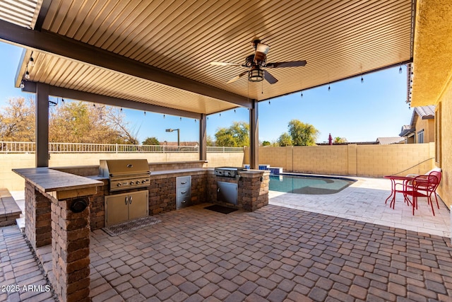 view of patio / terrace featuring ceiling fan, a grill, and exterior kitchen