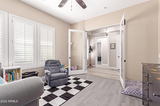 living area featuring light wood-type flooring, french doors, and ceiling fan