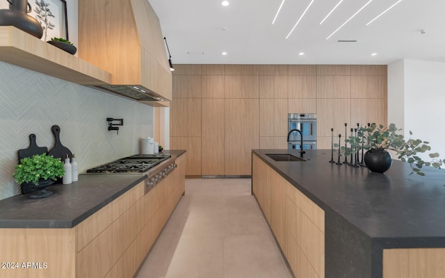 kitchen featuring sink, stainless steel gas cooktop, a spacious island, and light brown cabinets