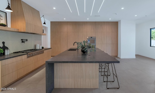 kitchen with pendant lighting, a breakfast bar, stainless steel gas cooktop, a large island with sink, and light brown cabinets