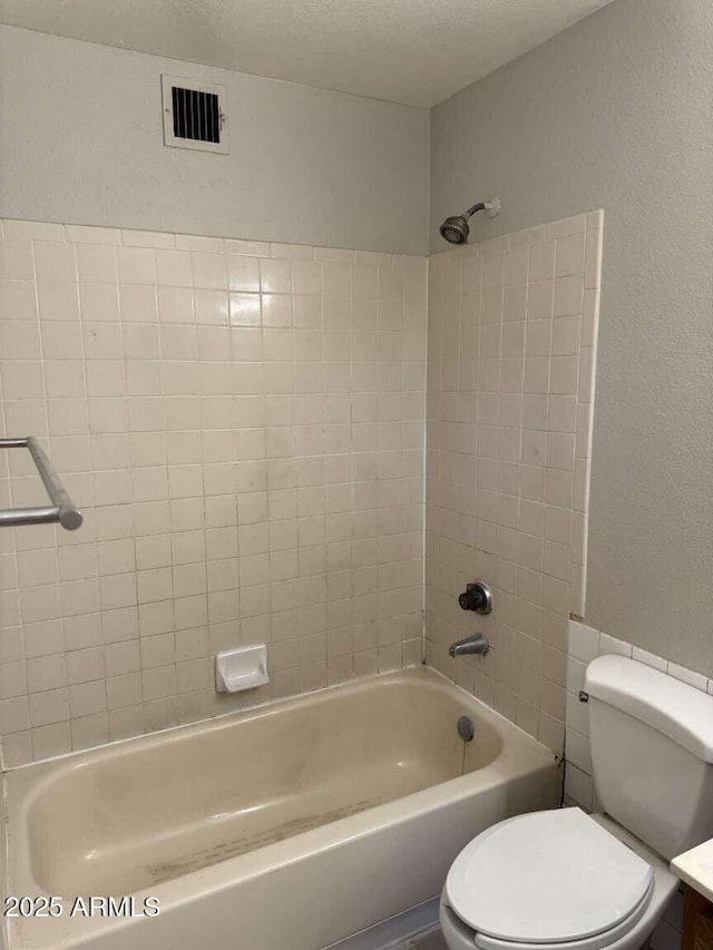 full bathroom with vanity, tiled shower / bath combo, a textured ceiling, and toilet