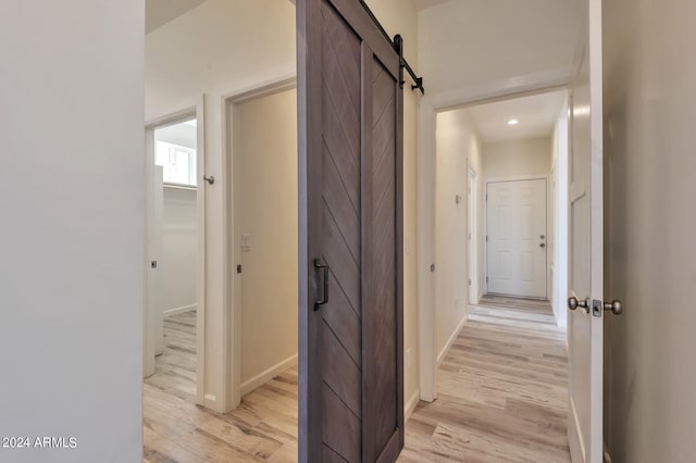 hallway featuring a barn door and light hardwood / wood-style flooring