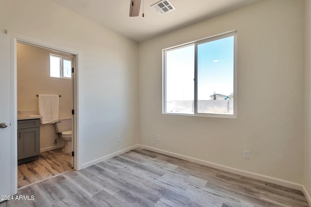 unfurnished bedroom with light hardwood / wood-style flooring, ceiling fan, and connected bathroom