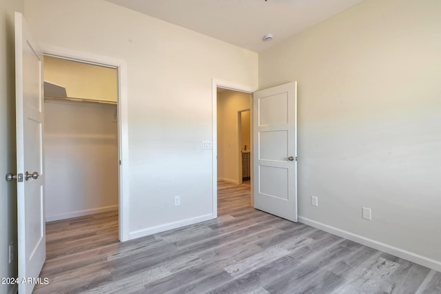 unfurnished bedroom featuring light wood-type flooring, a walk in closet, and a closet