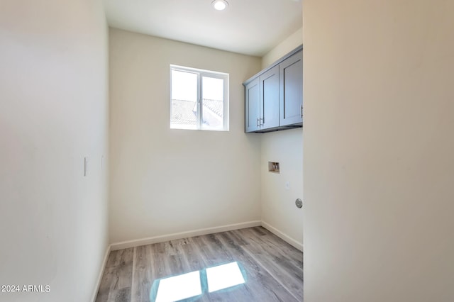 clothes washing area with light hardwood / wood-style flooring, washer hookup, and cabinets