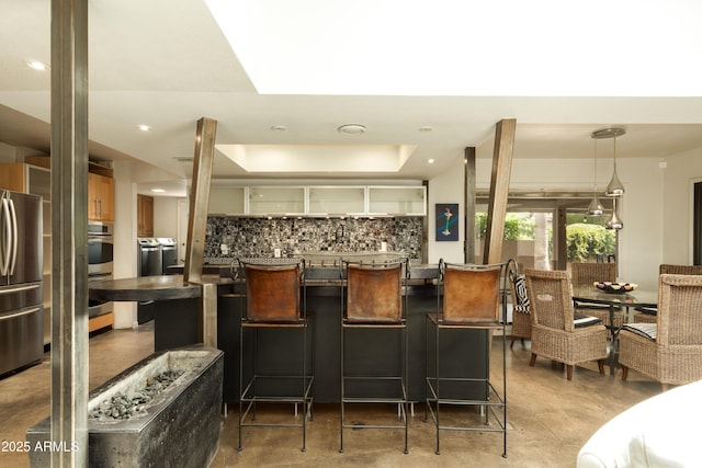4525 N 66th St Unit 112, Scottsdale, AZ 85251 - kitchen featuring freestanding refrigerator, decorative backsplash, a breakfast bar, finished concrete flooring, and recessed lighting