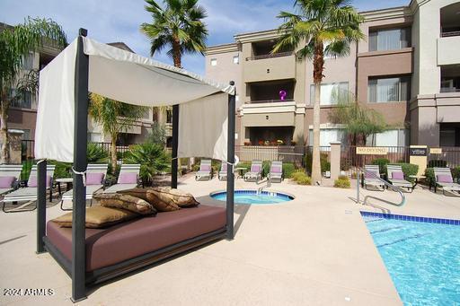 view of pool with a patio area, a community hot tub, and fence