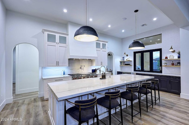 kitchen with light stone countertops, white cabinetry, a large island, and pendant lighting