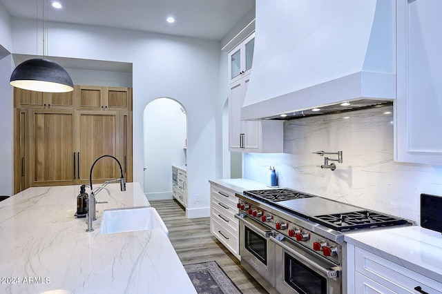 kitchen featuring white cabinets, premium range hood, and double oven range