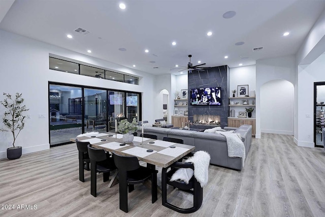 dining room with light hardwood / wood-style floors, a fireplace, and ceiling fan