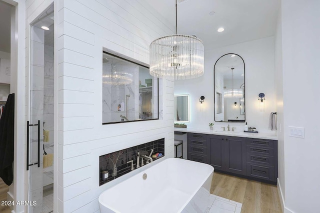 bathroom featuring wood-type flooring, vanity, plus walk in shower, and a notable chandelier