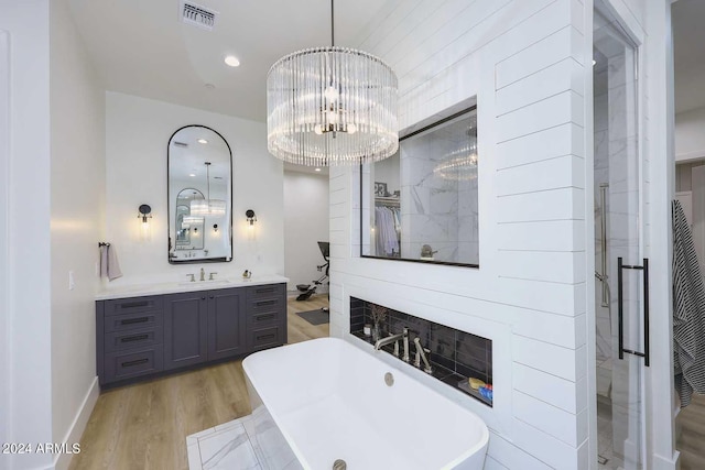 bathroom featuring vanity, lofted ceiling, an inviting chandelier, separate shower and tub, and hardwood / wood-style floors