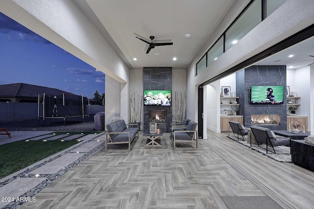 patio at twilight with an outdoor living space with a fireplace and ceiling fan